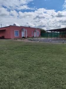 un edificio rojo con un campo de césped delante de él en Cabaña Sarita en Santa Rosa