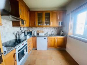 uma cozinha com armários de madeira e uma máquina de lavar louça branca em Casa Sonia Great location Quiet area Easy access em Óbidos