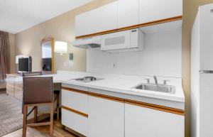 cocina con armarios blancos, fregadero y silla en Extended Stay America Select Suites - Orlando - Southpark - Equity Row, en Orlando