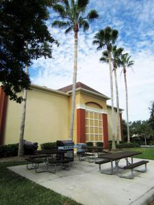 a house with three picnic tables and palm trees at Extended Stay America Suites - Clearwater - Carillon Park in Clearwater