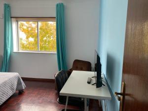 Zimmer mit einem Schreibtisch, einem Computer und einem Fenster in der Unterkunft Quarto casa familiar in Viseu