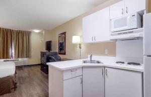 a kitchen with white cabinets and a sink in a room at Extended Stay America Suites - Pensacola - University Mall in Pensacola