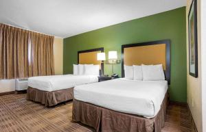 duas camas num quarto de hotel com paredes verdes em Extended Stay America Suites - Pensacola - University Mall em Pensacola