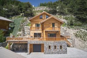 a large wooden house with a deck on a mountain at FRGK " Luxury Chalet" in Saint-Étienne-de-Tinée