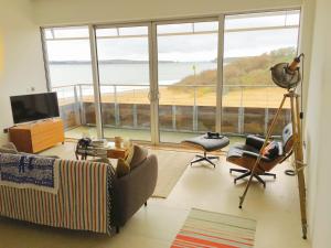 a living room with a couch and a large window at Eight Water's Edge in Tenby