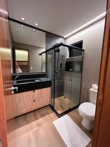 uma casa de banho com uma cabina de duche em vidro e um WC. em CASA ALTO DA ENSEADA PRAIA DO FORTE em Praia do Forte