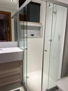 a bathroom with a glass shower and a sink at CASA ALTO DA ENSEADA PRAIA DO FORTE in Praia do Forte