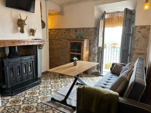 a living room with a fireplace and a wooden table at Casa De La Aguadora in Iznatoraf