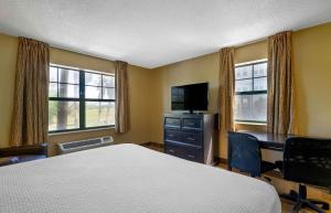 Extended Stay America Suites - Tampa - Airport - Spruce Street في تامبا: غرفة نوم بسرير ومكتب وتلفزيون