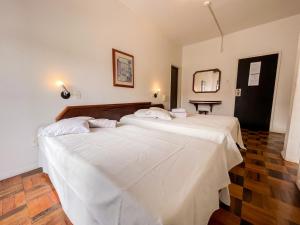 2 camas con sábanas blancas en una habitación en Canas Gold Praia Hotel, en Florianópolis