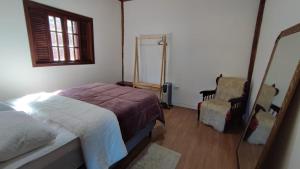 um quarto com uma cama, um espelho e uma cadeira em Rancho dos Mantas em Santo Antônio do Pinhal