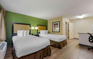 a hotel room with two beds and green walls at Extended Stay America Suites - Fort Lauderdale - Cypress Creek - Andrews Ave in Fort Lauderdale