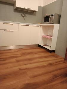 a kitchen with white cabinets and a wooden floor at MountainAosta - CIR 0062 in Aosta