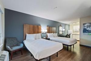 a hotel room with two beds and a chair at Extended Stay America Suites - Miami - Airport - Blue Lagoon in Miami