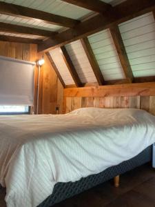 a bed in a room with wooden walls and ceilings at A Modo Mío in San Carlos de Bariloche