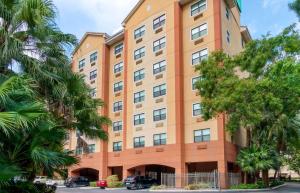 ein hohes Orangengebäude mit Bäumen davor in der Unterkunft Extended Stay America Premier Suites - Miami - Coral Gables in Miami