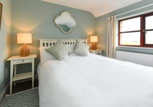 a bedroom with a white bed with two tables and a mirror at Trefaes Bach in Abersoch