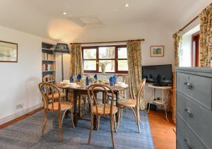 a dining room with a table and chairs and a television at Trefaes Bach in Abersoch