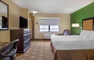 a hotel room with a bed and a flat screen tv at Extended Stay America Suites - Boston - Braintree in Braintree