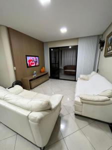 sala de estar con 2 sofás blancos y TV en Apartamento familiar com vista para o mar em Guarapari Praia do Morro, frente ao Marlim!!!, en Guarapari