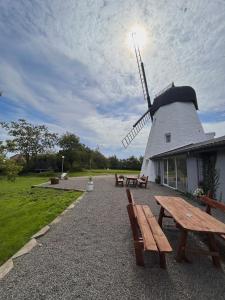 a windmill with two picnic tables and a building at Apartamenty Molle in Åkirkeby