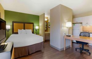 a bedroom with a bed and a desk and a kitchen at Extended Stay America Suites - Boston - Woburn in Woburn