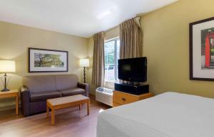 a hotel room with a bed and a couch and a television at Extended Stay America Suites - Boston - Woburn in Woburn