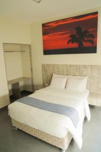 1 dormitorio con 1 cama blanca grande y una pintura en la pared en Low Cost Business Hotel, en Piura