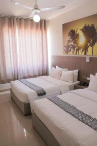 2 camas en una habitación de hotel con ventanas en Low Cost Business Hotel, en Piura