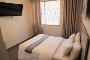1 dormitorio con 1 cama, TV y ventana en Low Cost Business Hotel, en Piura