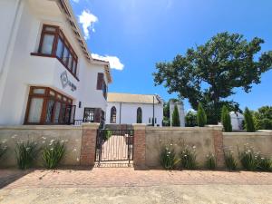 una casa blanca con una valla y un árbol en La Maison On Main Self-Catering Villa en Paarl