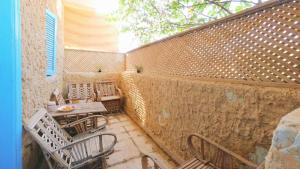 an outdoor patio with chairs and tables and a wall at هوستل أجبناخ إنشالي Hostel Agbenakh Inshaly in Siwa