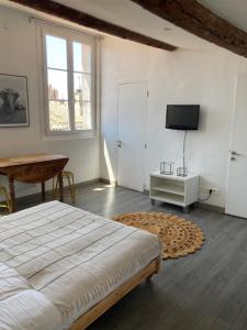 a bedroom with a bed and a table and a television at La Maison sur les Toits in Aix-en-Provence