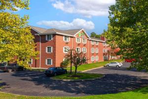 um grande edifício de tijolos com carros estacionados num parque de estacionamento em Extended Stay America Suites - Hartford - Farmington em Farmington