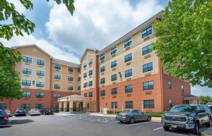 un gran edificio con coches estacionados en un estacionamiento en Extended Stay America Suites - Secaucus - Meadowlands, en Secaucus