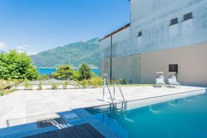 a swimming pool with two chairs next to a building at ANNA'S LODGE QUITE & CHARME in Pianello Del Lario