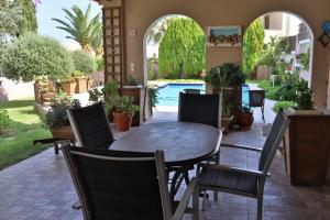 un patio con tavolo, sedie e piscina di Olive Villa Crete a Rethymno