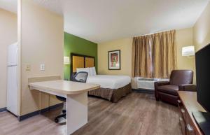 a small hotel room with a bed and a desk at Extended Stay America Suites - Syracuse - Dewitt in East Syracuse