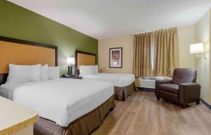 a hotel room with two beds and a chair at Extended Stay America Suites - Syracuse - Dewitt in East Syracuse