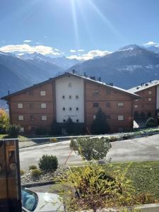a large building with snow capped mountains in the background at Appartement l Magnifique vue l Proche Crans-Montana in Crans-Montana
