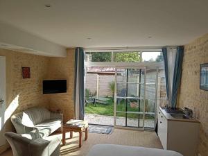 a living room with a couch and a kitchen with a window at Villa kahlo Omaha Beach in Colleville-sur-Mer