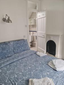 a bedroom with a blue bed with a fireplace at Cosy Irish Cottages RDS in Dublin