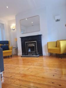 a living room with a fireplace and two yellow chairs at Cosy Irish Cottages RDS in Dublin