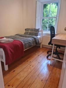 a bedroom with a bed and a desk and a window at Cosy Irish Cottages RDS in Dublin