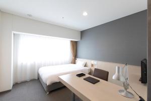 a hotel room with a bed and a desk with a desk at X wave Funabashi in Funabashi