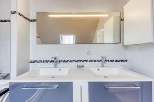 een badkamer met een witte wastafel en een spiegel bij Loft à 15 min des Champs-Élysées Paris avec parking in Clichy
