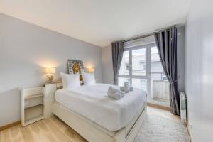 een witte slaapkamer met een groot bed en een raam bij Loft à 15 min des Champs-Élysées Paris avec parking in Clichy