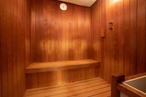 船橋的住宿－船橋X波酒店，一间设有木墙和墙上时钟的桑拿浴室