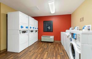 a laundry room with white washers and a red wall at Extended Stay America Suites - Washington, DC - Chantilly - Dulles South in Chantilly