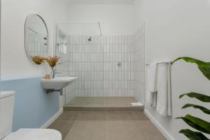 een witte badkamer met een wastafel en een spiegel bij Neighbourgood Franschhoek in Franschhoek